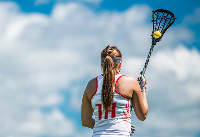 Women's lacrosse player against the sky