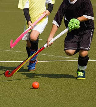 Children,Playing,Field,Hockey,Competitively.,Two,Teammates,In,Yellow,Jerseys Hockey players