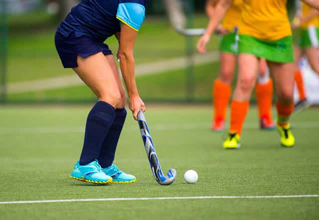 Young hockey player woman with ball in attack playing field hockey game