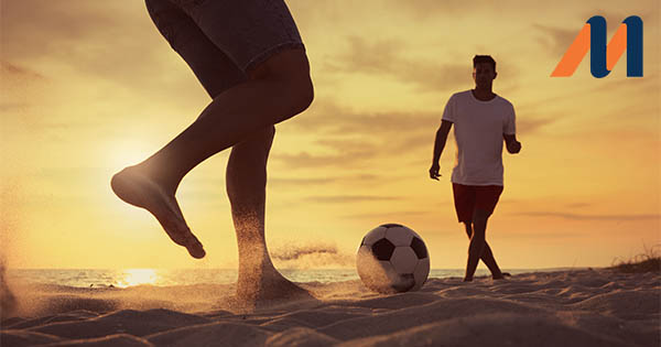 Football players on the beach at sunset