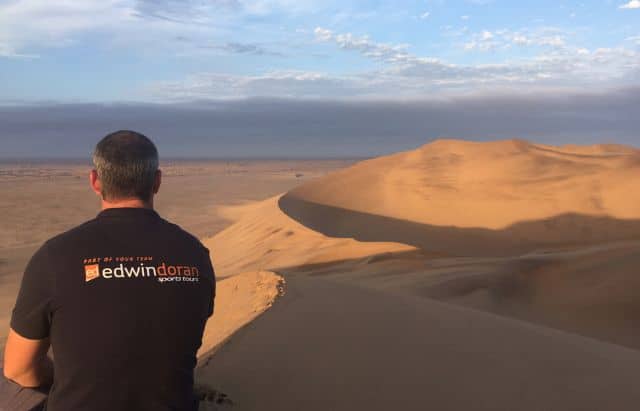 Person wearing an Edwin Doran shirt on a sandy dune in Namibia