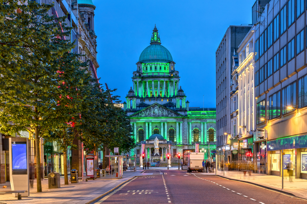 Belfast City Hall illuminated with bright green colours at dusk