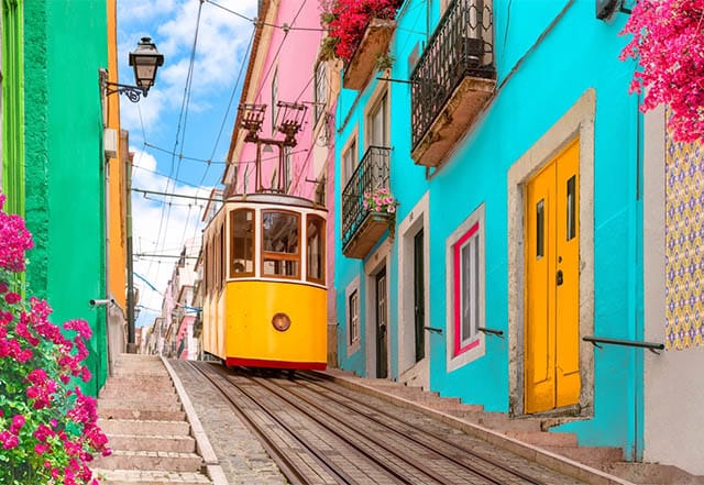 A yellow tram in Lisbon with colourful houses in the background