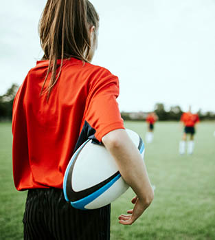 Femail rugby player holding the ball under her arm