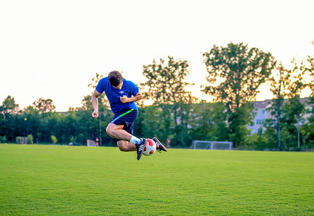 Football player training alone on the pitch, early on the morning