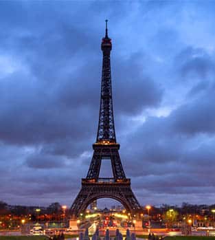 Eiffel Tower at sunrise with clouds and city lights from Trocadero, Paris, France