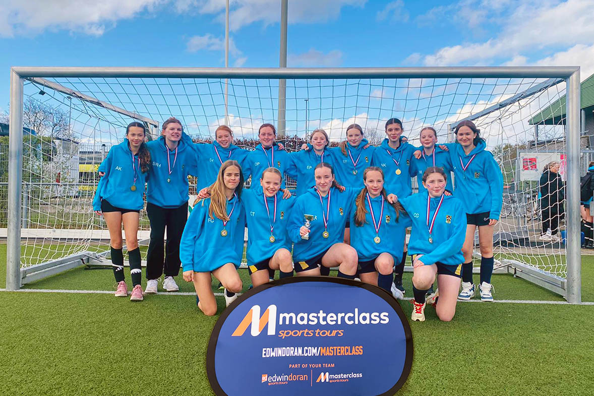 Girls football team posing in front of goal with a Masterclass flag