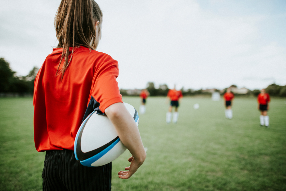 Girl rugby player holding the ball in her arms