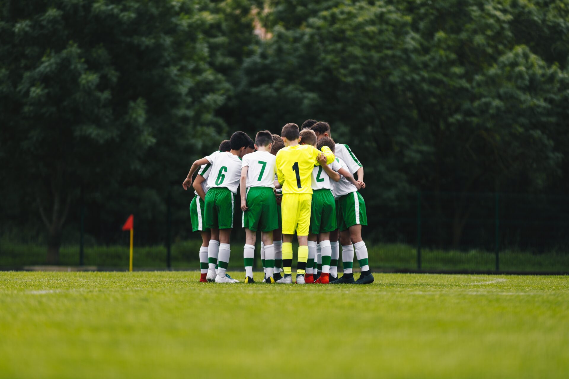 Young boys football players huddling during a training session