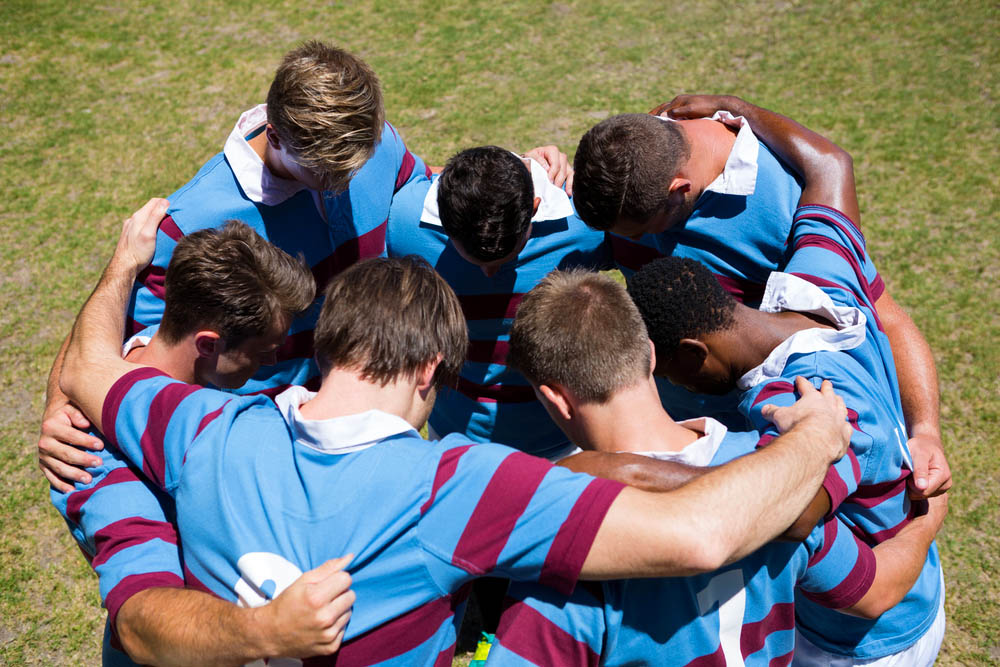 Boys team huddle at a rygby game