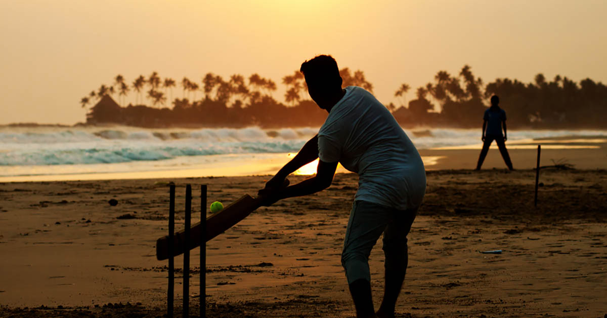 Boy playing cricket at sunset on tropical beach in Sri Lanka