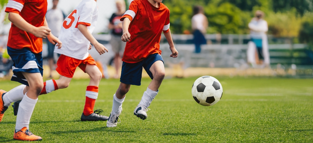 Boys playing football in red and white jerseys