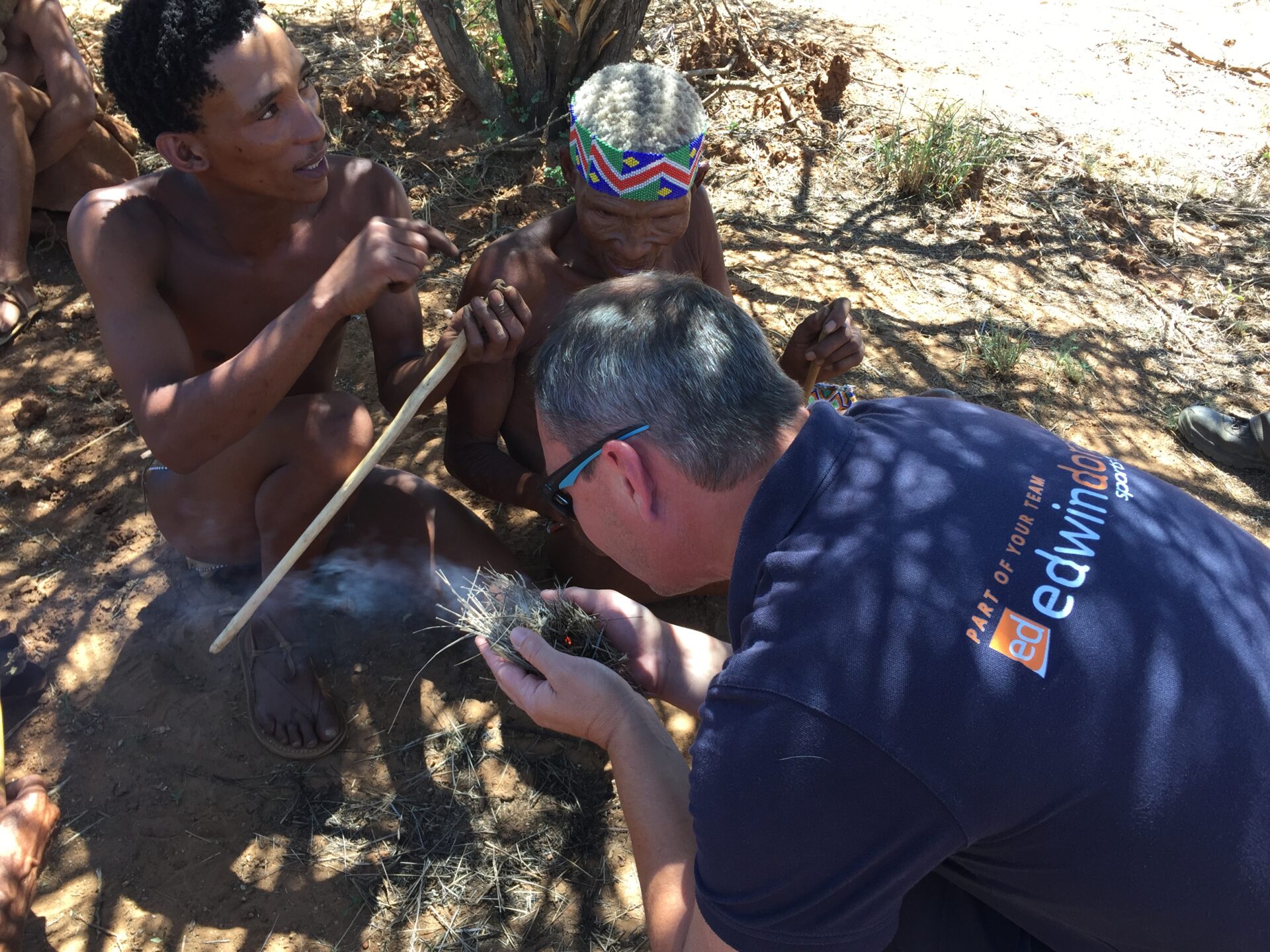 Sean wearing an Edwin Doran jersey and making a fire with the Na'an Ku Se tribe in Namibia