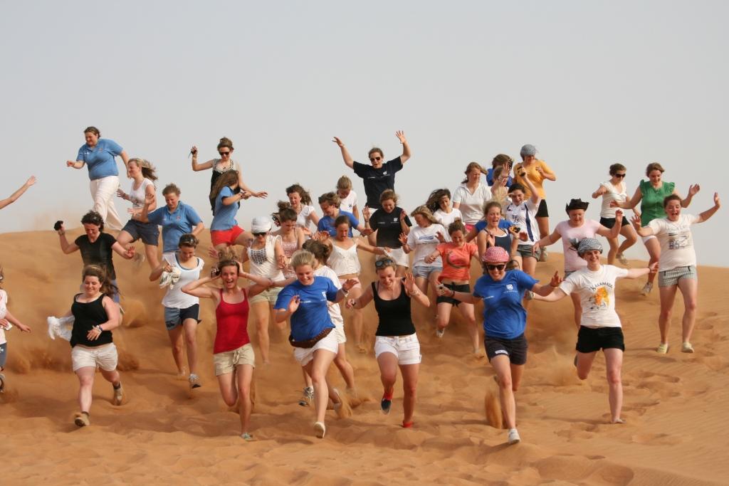 Group running down a sand dune in Namibia